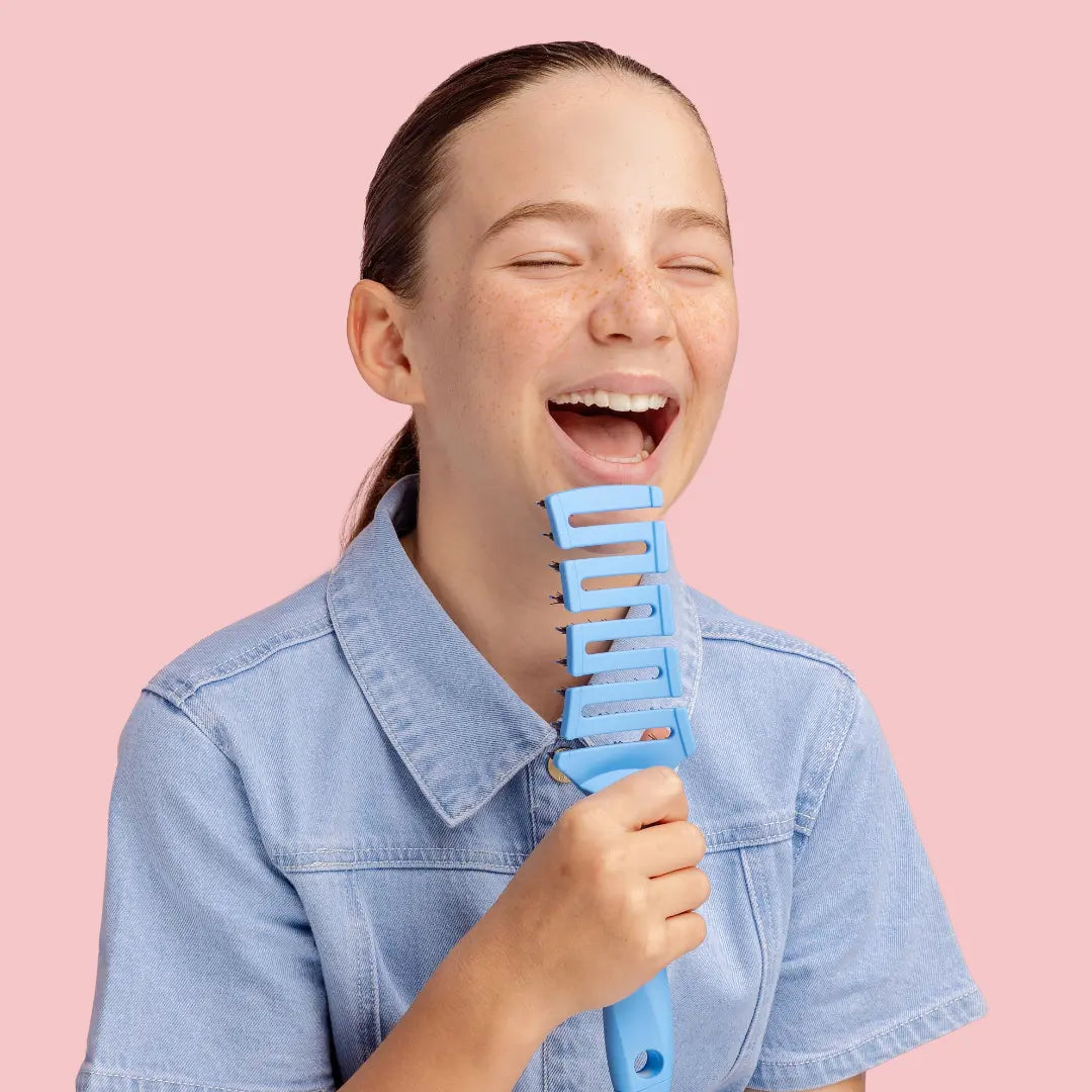 Girl holding a blue comb against a pink background