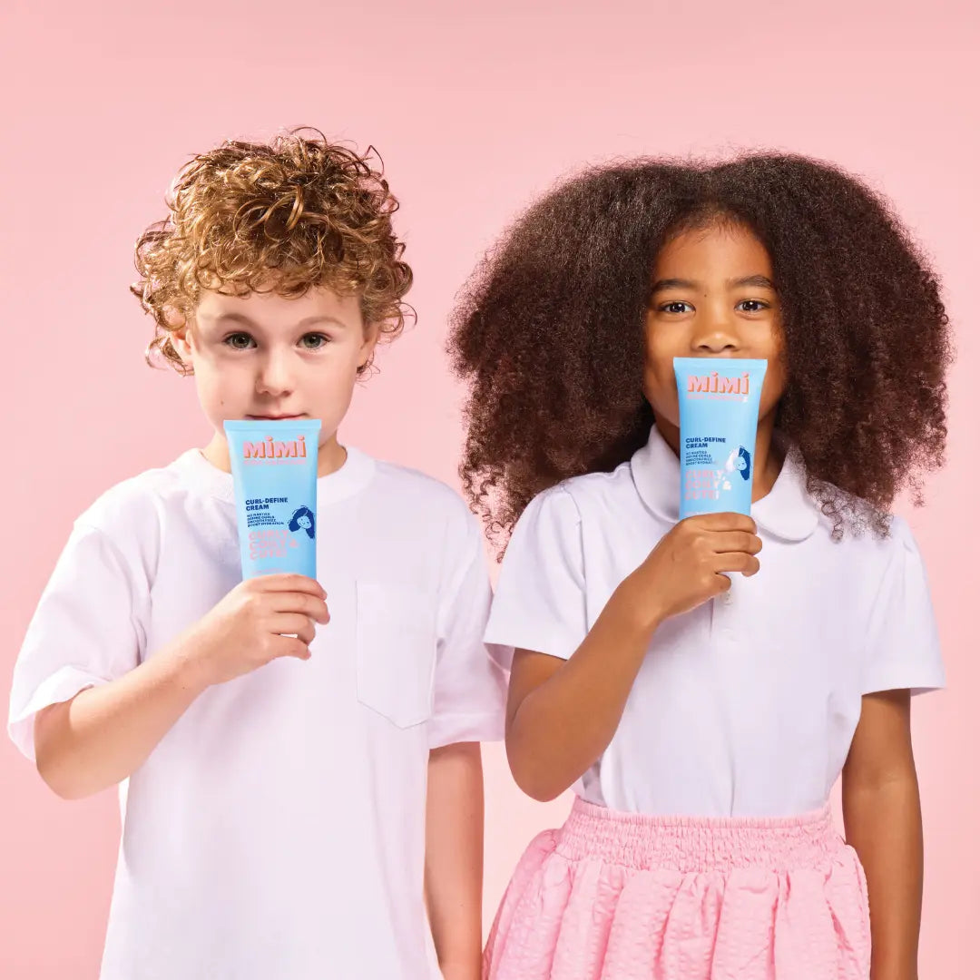 Two children holding blue Mimi haircare products against a pink background