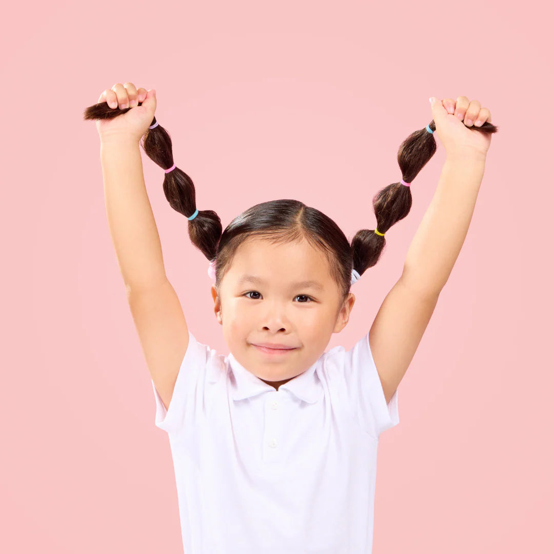 Child with pigtails against a pink background